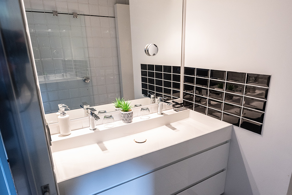 Un meuble de salle de bain avec un évier, des rangements et un miroir dans une chambre du Domaine de Béronsart