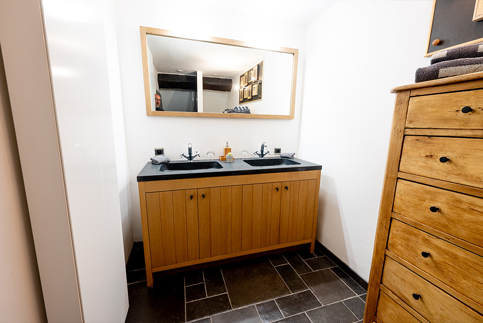 Un meuble double vasque en bois, un miroir et une armoire dans une chambre du Domaine de Béronsart