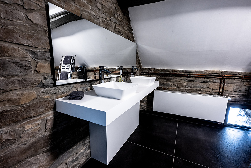 Coin salle de bain d'une chambre du Domaine de Béronsart avec une double vasque blanche et un grand miroir