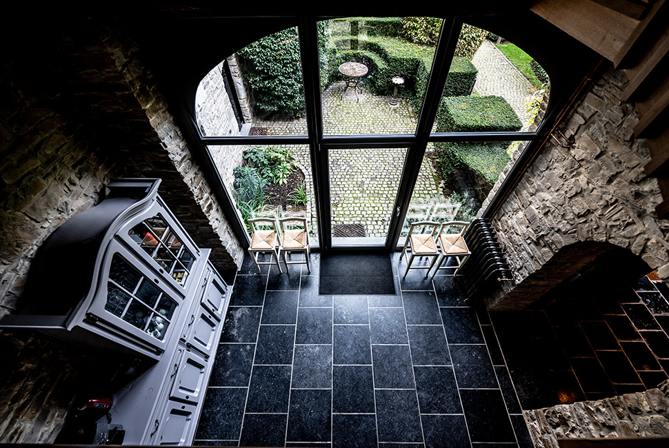 Intérieur du Grand Hall du Domaine de Béronsart : sol en pavé noir, pierres apparentes aux murs