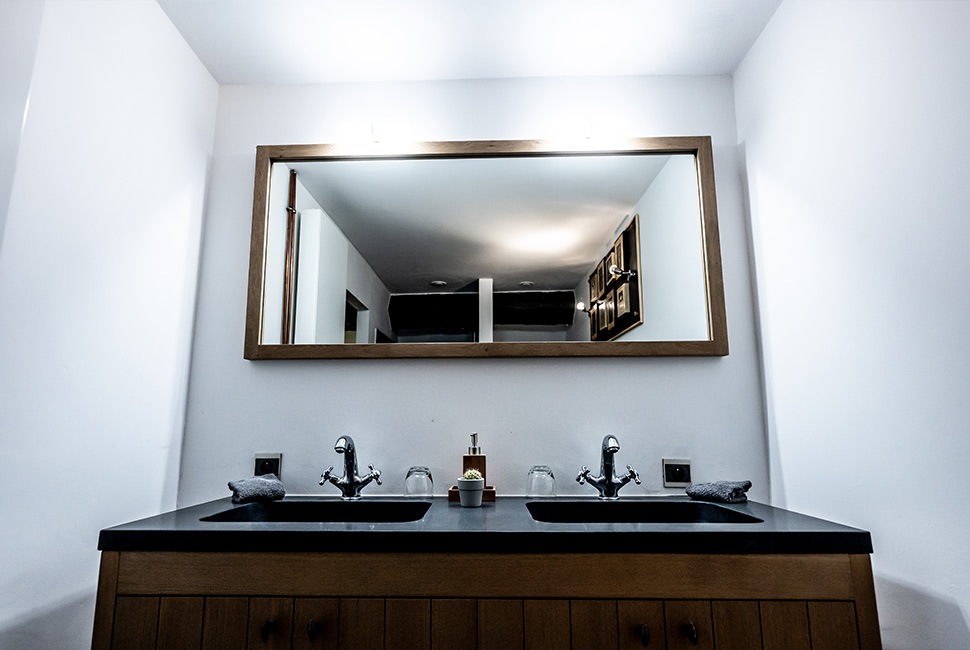 Le coin lavabo d'une chambre du Domaine de Béronsart avec un grand miroir et un meuble double vasque
