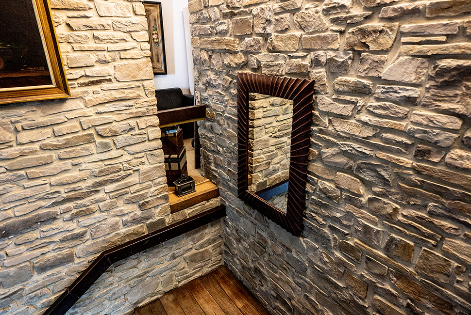 Escalier de la Salle de Réception du Domaine de Béronsart avec des murs en pierres apparentes et des cadres