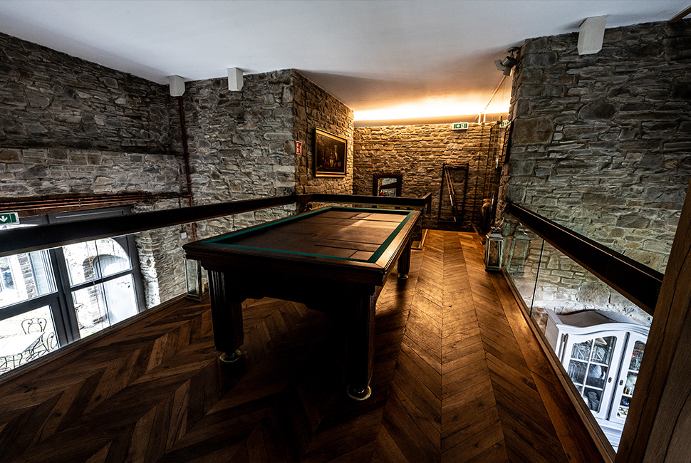 Étage du Grand Hall du Domaine de Béronsart avec un billard et du parquet en bois au sol