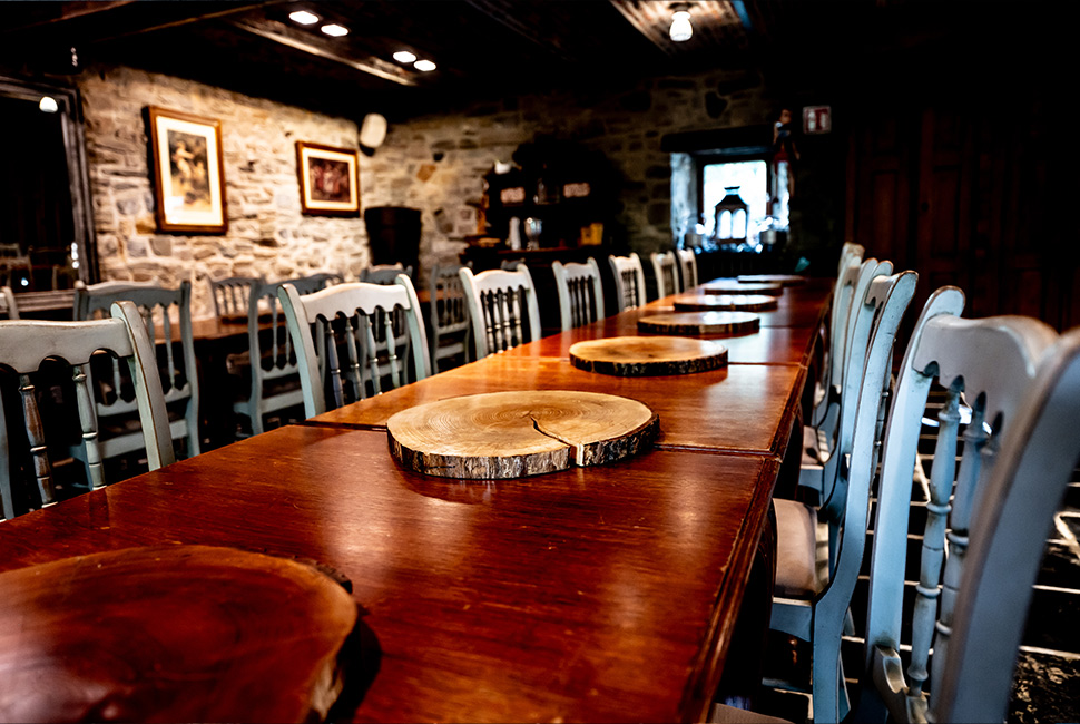 Salle de réception du Domaine de Béronsart avec des tables en bois, des rondins de bois pour poser les plats/boissons